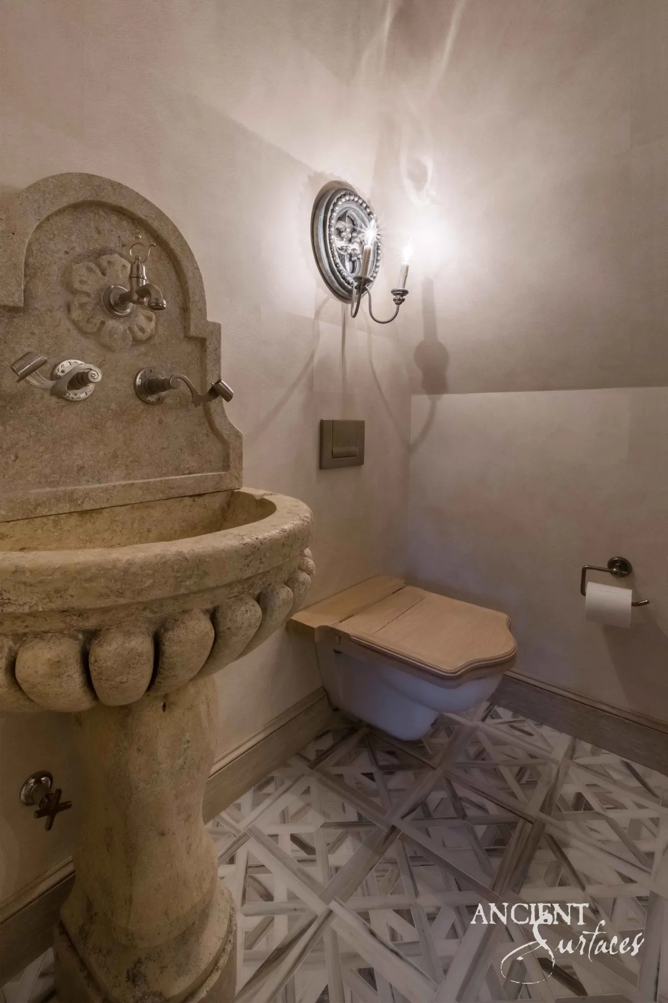 Reclaimed antique limestone pedestal sink from Ancient Surfaces with a scalloped basin and carved backplate, installed beside a wall hung toilet in a compact powder room