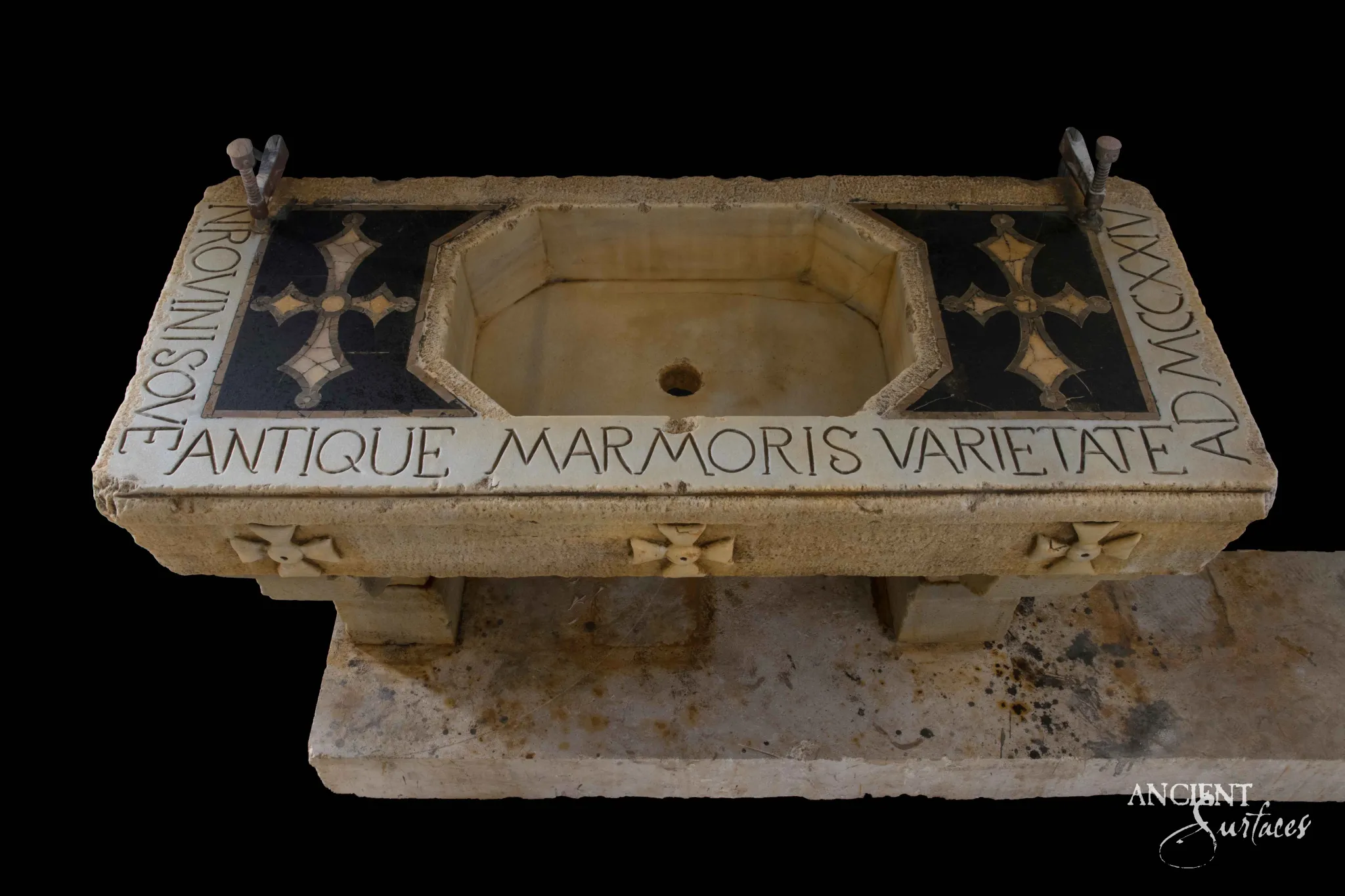Reclaimed antique limestone trough sink from Ancient Surfaces with an octagonal basin, inlaid dark stone crosses and a carved Latin inscription dated MCCXXI, photographed against black
