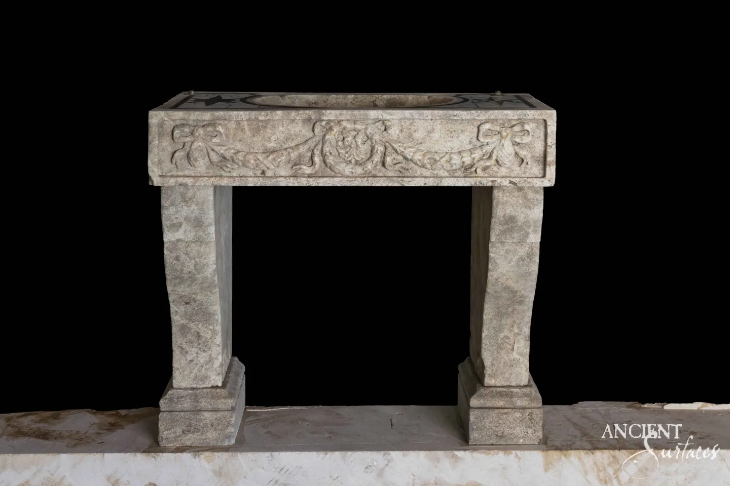 Reclaimed antique limestone vessel sink from Ancient Surfaces with a hand shaped rounded basin, set on a stone counter in a warmly lit travertine tiled bathroom